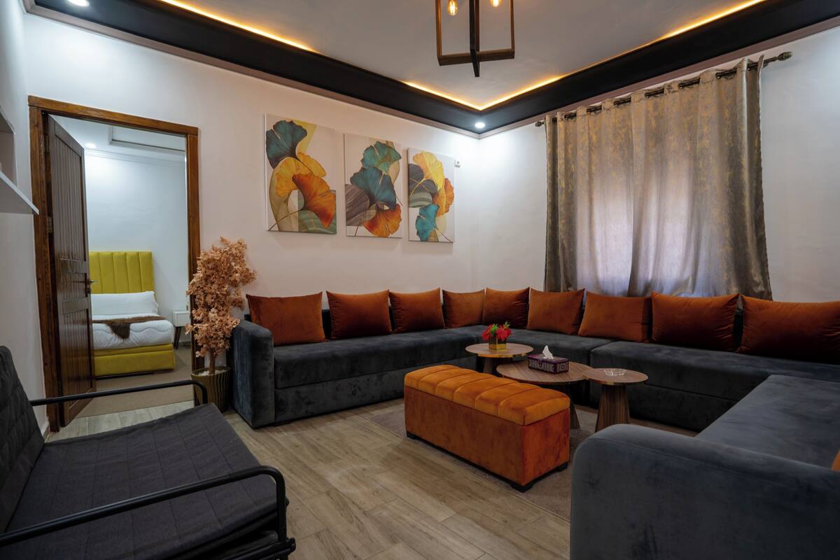 A modern living room with a sofa set, a coffee table, and a decorative plant.
