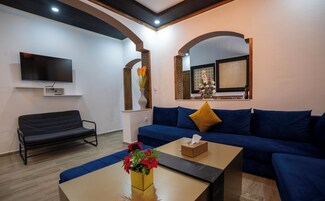 Una sala de estar con un sofá, una mesa de centro, un televisor y objetos decorativos.