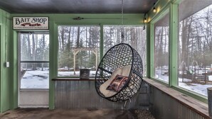 A bait shop with a hanging chair and a view of a snowy forest.