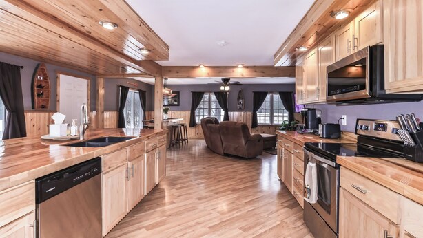A modern kitchen with wooden cabinets, a dishwasher, and a large stove.