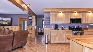 A modern kitchen with wooden cabinets, a stainless steel stove, and a microwave.