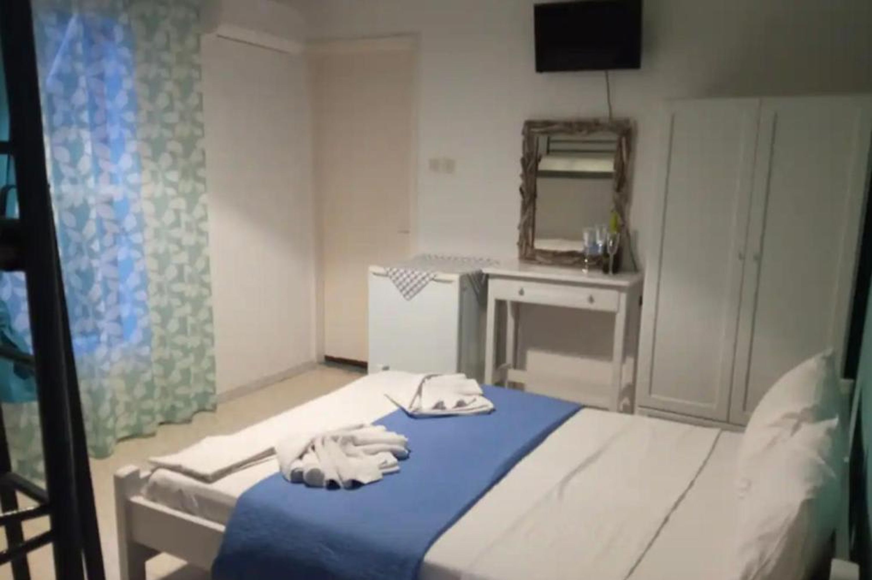 A hotel room with a bed, a bedside table, a mirror, and a wardrobe.
