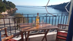 A wooden table with two chairs on a balcony overlooking a body of water.