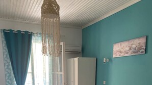 A bedroom with two beds, a wardrobe, a hanging light fixture, and a painting on the wall.