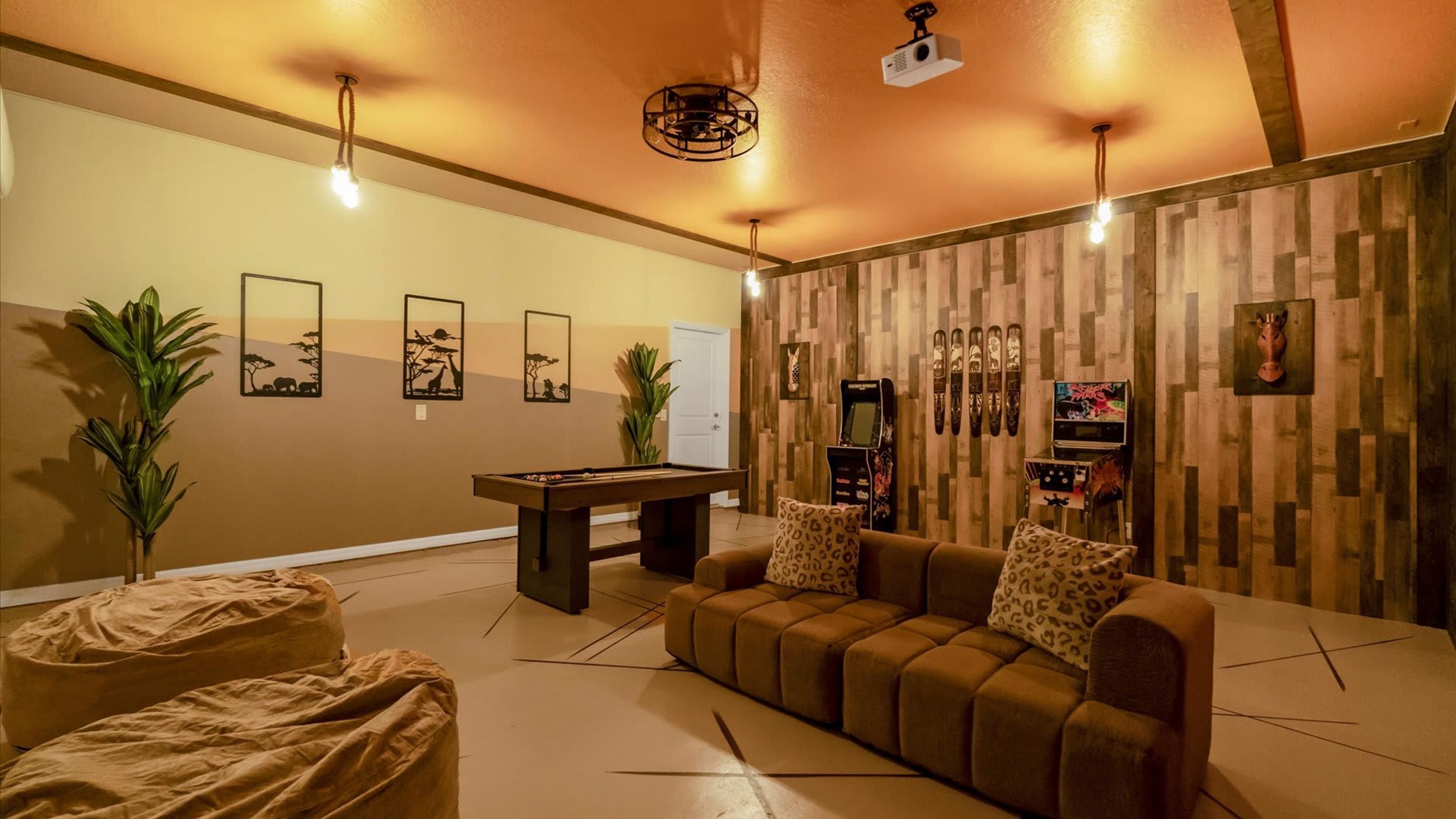 Une pièce chaleureuse avec une table de billard, un canapé et un mur en bois agrémenté de diverses décorations.