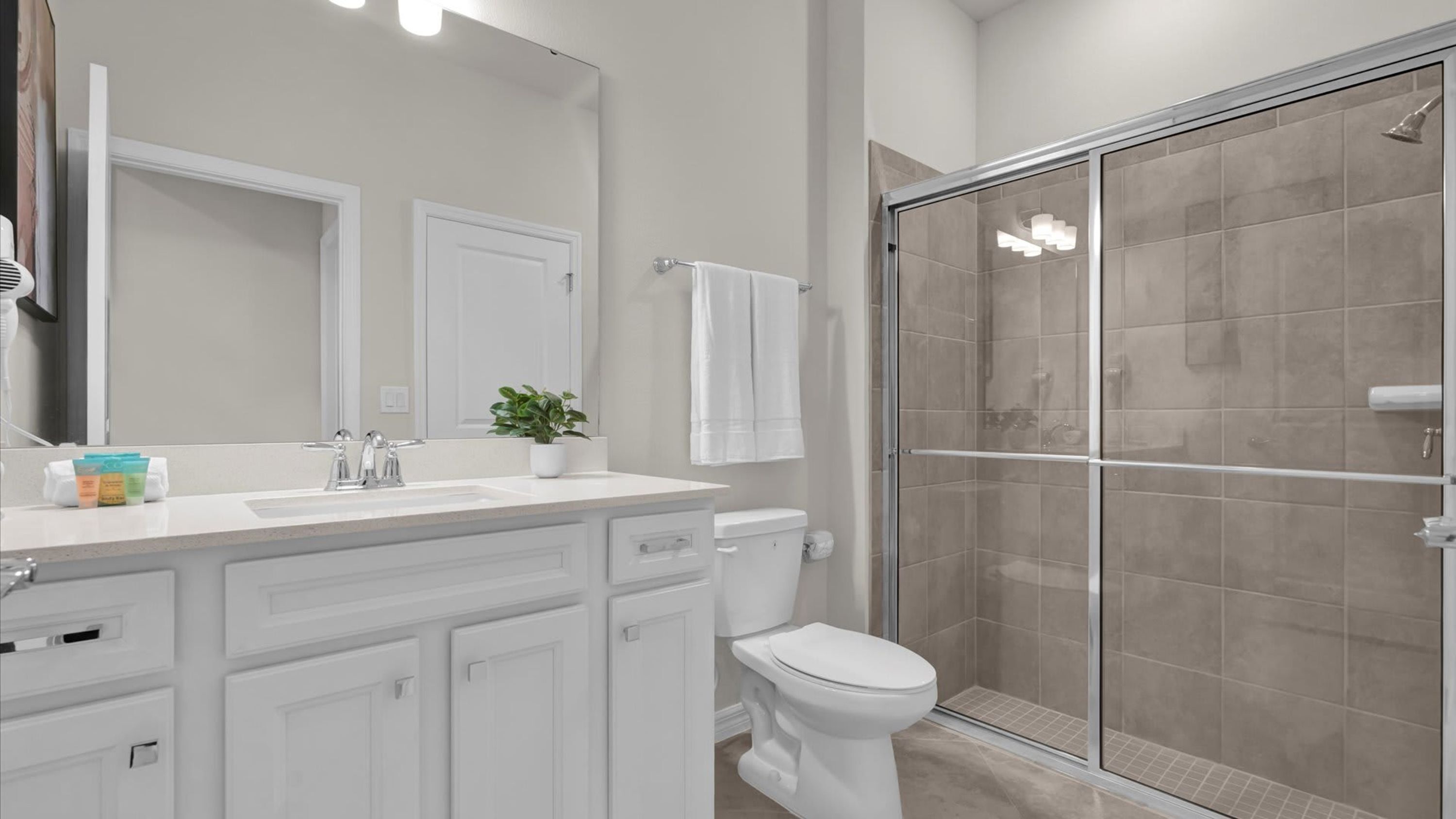 A modern bathroom with a white vanity, a toilet, and a glass-enclosed shower.