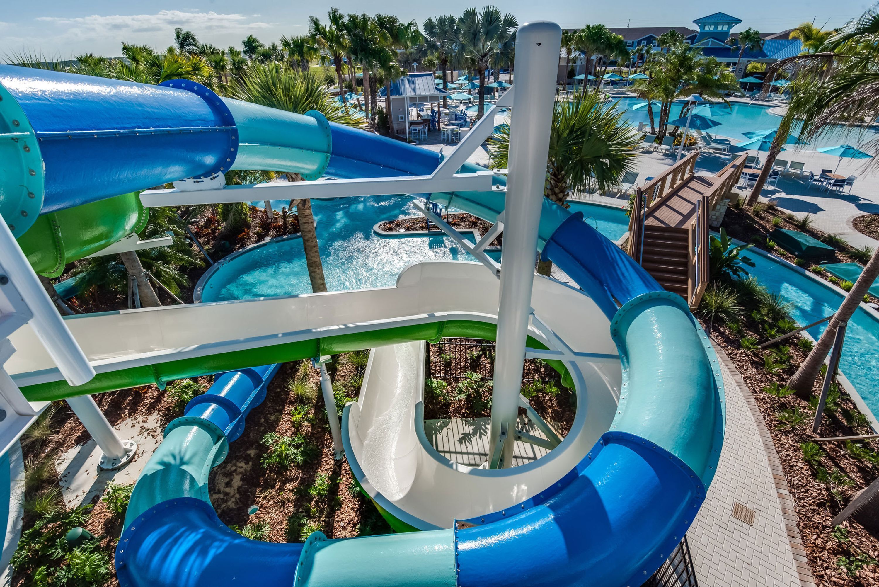 A water park with multiple slides and pools, surrounded by palm trees and lounge areas.