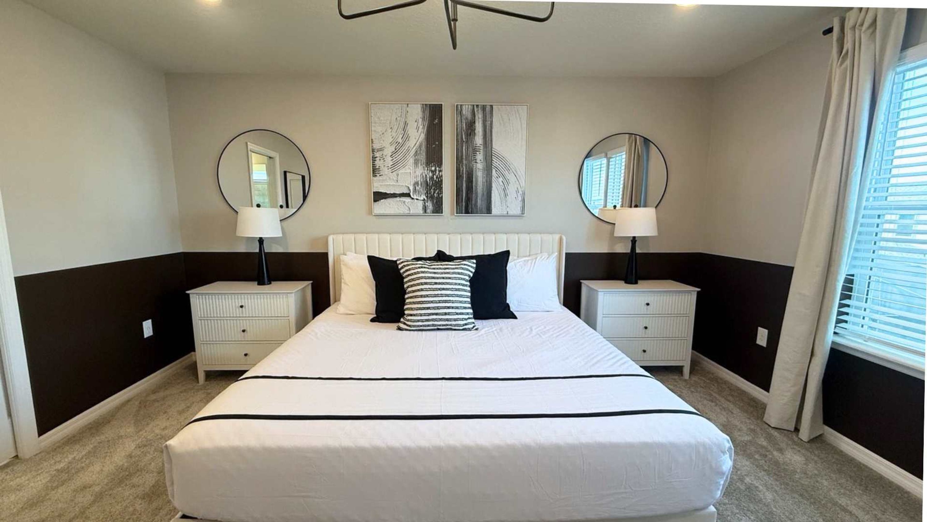Ein Hotelzimmer mit einem großen Bett, zwei Nachttischen, zwei Wandspiegeln und einem Kunstwerk über dem Bett.