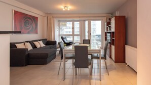 Un salon moderne comprenant un canapé, une table à manger, des chaises et une bibliothèque.