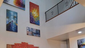 Ein großzügiger Wohnbereich mit Treppe, mehreren Kunstwerken an den Wänden und zwei Sofas.
