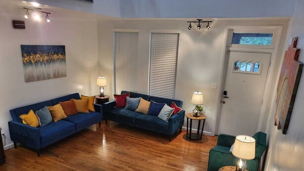 Ein Wohnzimmer mit einem blauen Sofagarnitur, zwei Beistelltischen mit Lampen und einem grünen Sessel.