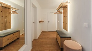 A hallway with wooden lockers, a bench, and a round stool. - Garden 5 - Apartment 4 (Braunlage)