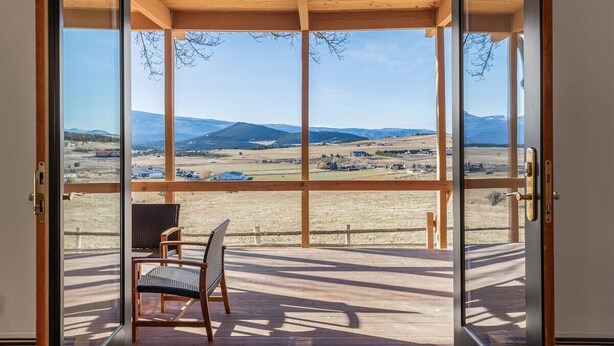 A room with a large glass door leading to an outdoor deck with a view of a mountainous landscape. - Southwestern Casita with A/C, Sopris Views & Fenced Yard Near Aspen & Carbondale (Carbondale)