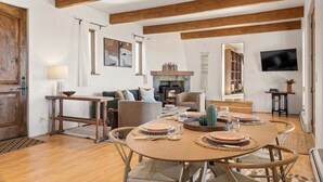 A spacious living room with a wooden dining table set for four, a fireplace, and a television mounted on the wall. - Southwestern Casita with A/C, Sopris Views & Fenced Yard Near Aspen & Carbondale (Carbondale)