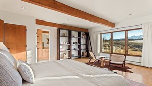 A bedroom with a large bed, a wooden ceiling, a bookshelf, a desk, and a view of a mountainous landscape. - Southwestern Casita with A/C, Sopris Views & Fenced Yard Near Aspen & Carbondale (Carbondale)