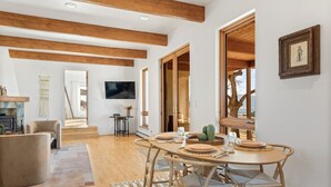 A spacious living area with a wooden ceiling, a dining table set with plates and glasses, and a television mounted on the wall. - Southwestern Casita with A/C, Sopris Views & Fenced Yard Near Aspen & Carbondale (Carbondale)