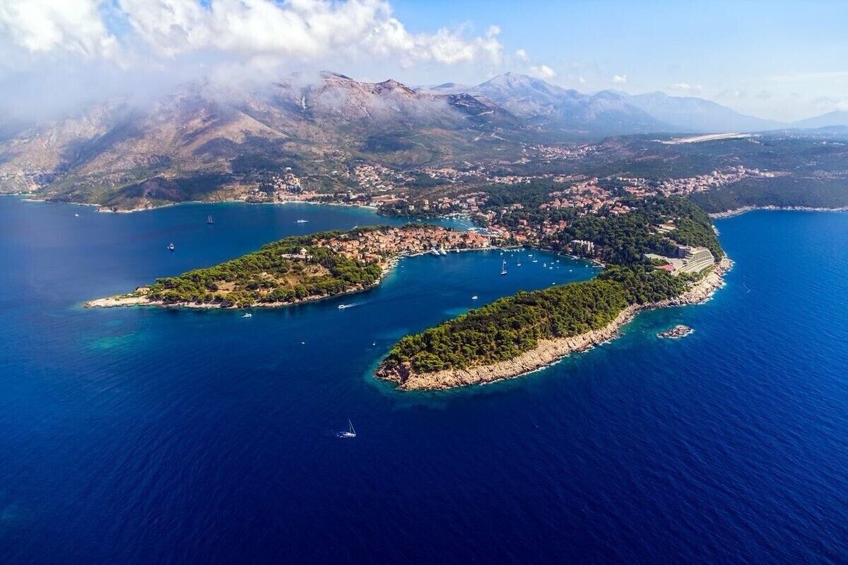 An aerial view of a coastal town with a bay, surrounded by mountains.