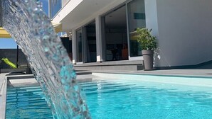 A modern building with a pool, a water feature, and a potted plant.