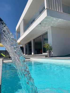 Un edificio moderno con piscina, fuente de agua y una planta en maceta.