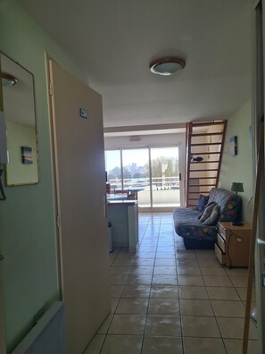 Relax in this open-plan living area with a kitchenette, sofa, and large window offering a view of the outdoors.