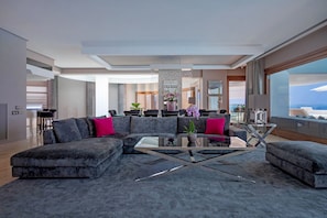 A modern living room with a sectional sofa, a glass coffee table, and a view of the city.