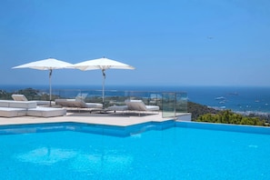 Une piscine dotée de chaises longues et de parasols, offrant une vue sur la côte.