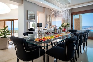 A modern dining area with a glass table, black upholstered chairs, and a view of the city.