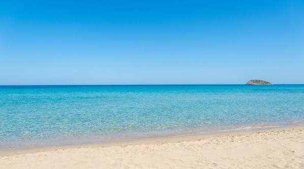 Une plage à l’eau turquoise et limpide, bordée d’un rivage sablonneux.