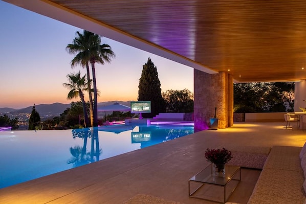 A modern outdoor pool area with a view of the mountains at dusk.