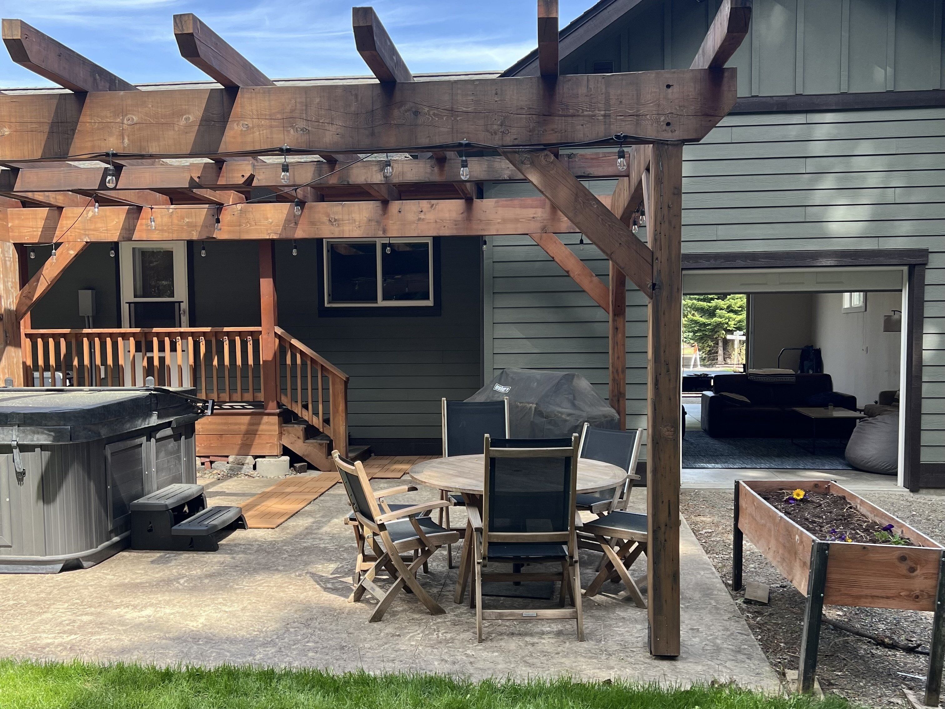 Ein überdachter Patio-Bereich mit einer Holzhütte, Sitzgelegenheiten im Freien und einem Whirlpool.
