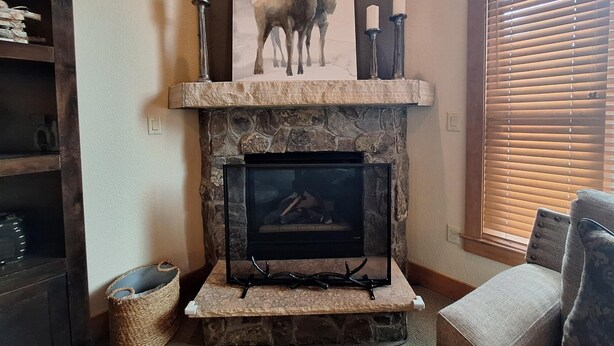 A stone fireplace with a mounted television, a deer painting above it, and two candles on the mantel. - 3br Red Hawk Townhome - Gondola Access 3 Bedroom Townhouse (Keystone)