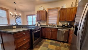 A kitchen with wooden cabinets, a stainless steel refrigerator, a gas stove, and a dishwasher. - 3br Red Hawk Townhome - Gondola Access 3 Bedroom Townhouse (Keystone)