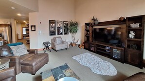 A living room with a large flat-screen TV, a brown leather sofa, a patterned rug, and a wooden entertainment center. - 3br Red Hawk Townhome - Gondola Access 3 Bedroom Townhouse (Keystone)