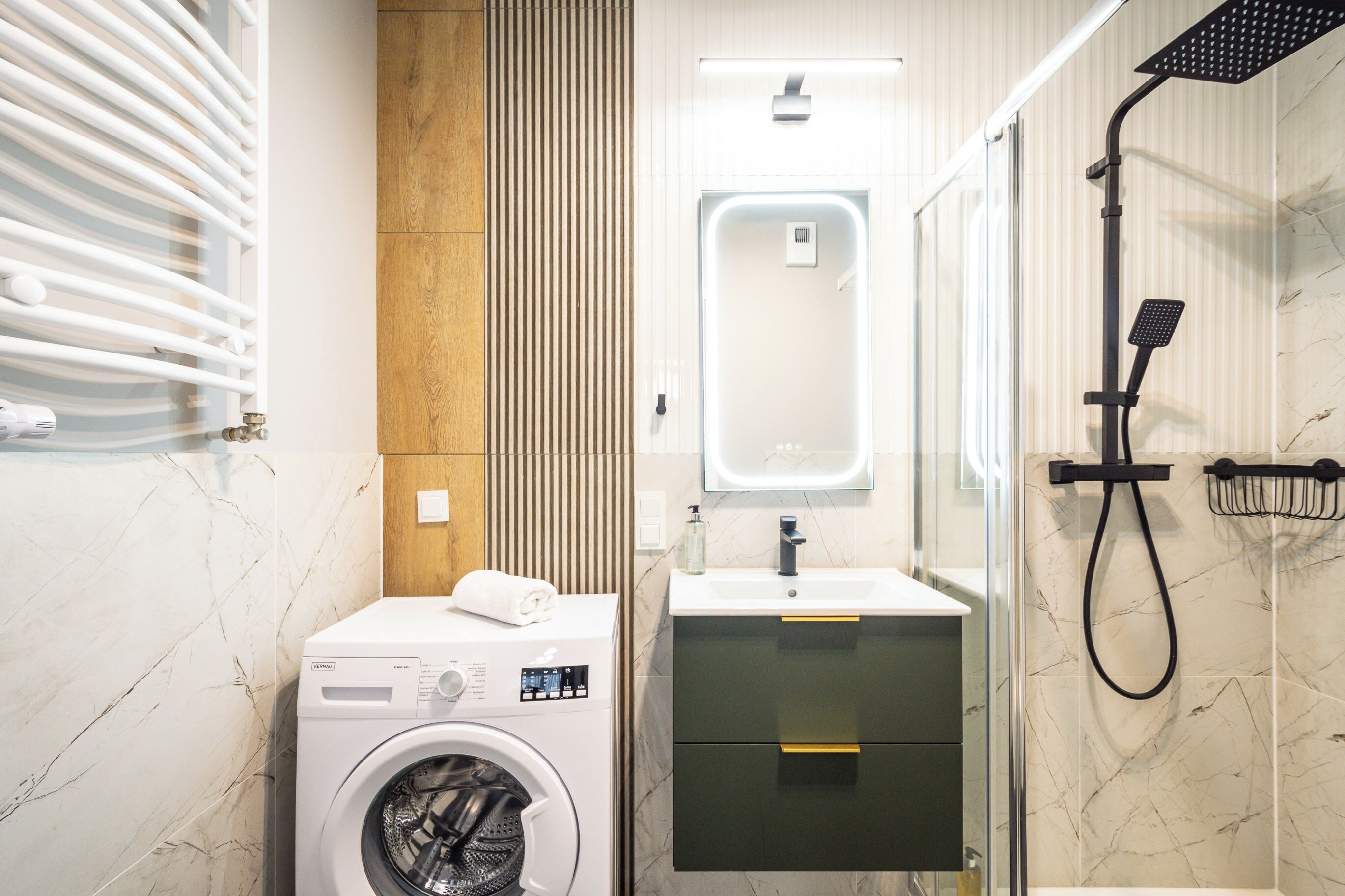 Un baño moderno con lavadora, lavabo y ducha.