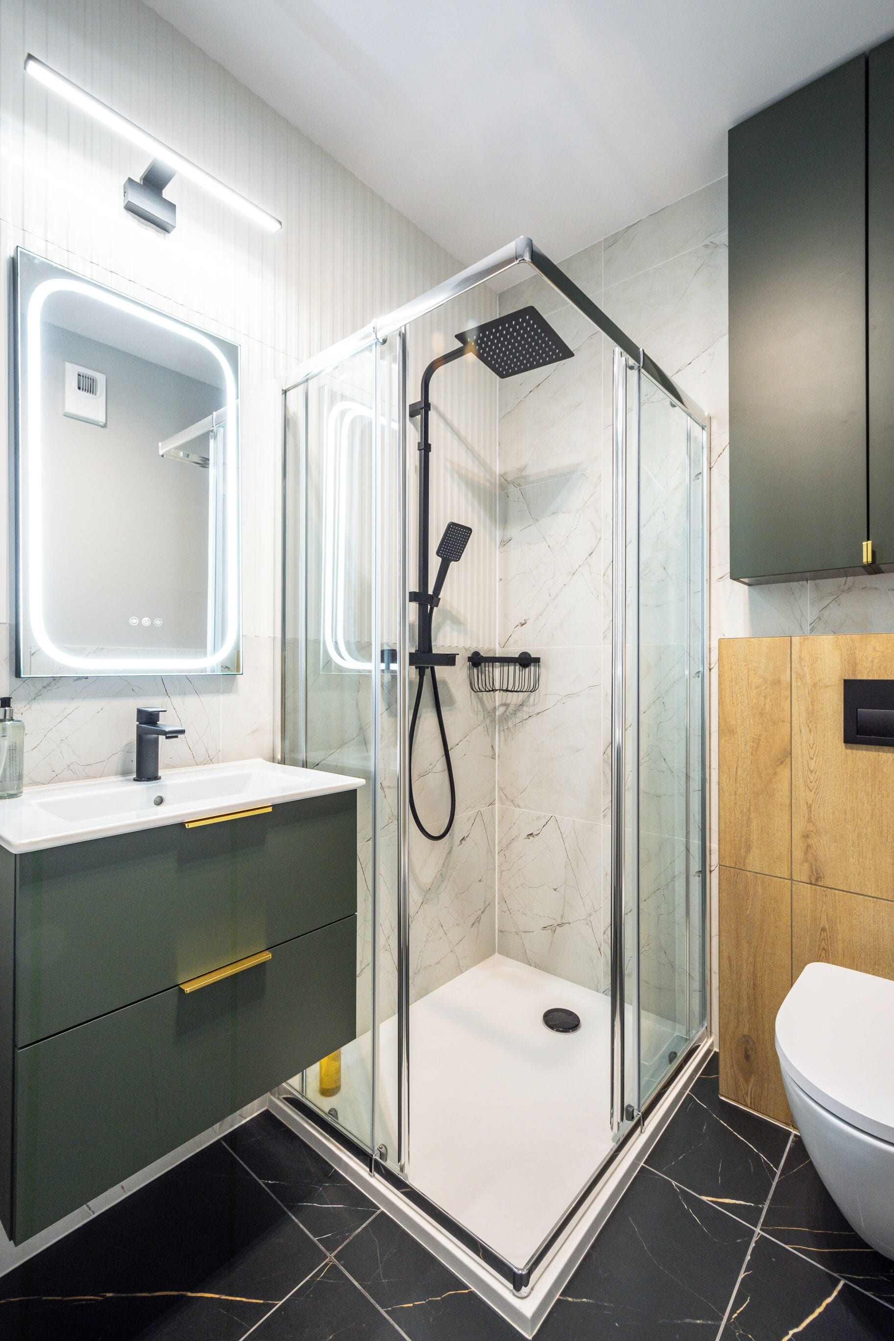 Un baño moderno con ducha envuelta en vidrio, lavamanos blanco con espejo y un mueble de madera.