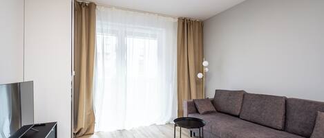 Una sala moderna con un sofá, un televisor y una mesita.