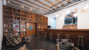 A bar area with wooden shelves stocked with bottles, a round wooden door, and bar stools. - Hotel ALBRECHT (Bratislava)