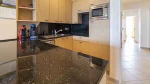 Une cuisine moderne dotée d’un plan de travail en granit, d’appareils électroménagers en acier inoxydable et de meubles en bois.