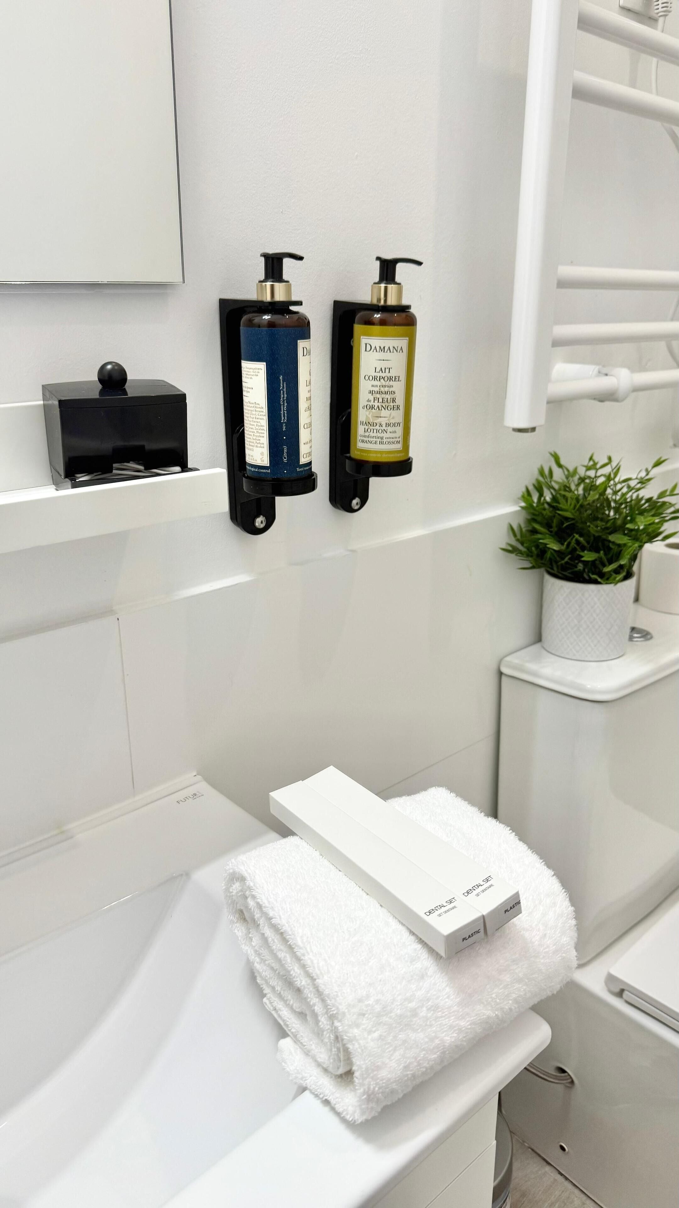 A bathroom with a white sink, a towel, and two hand and body lotion dispensers.