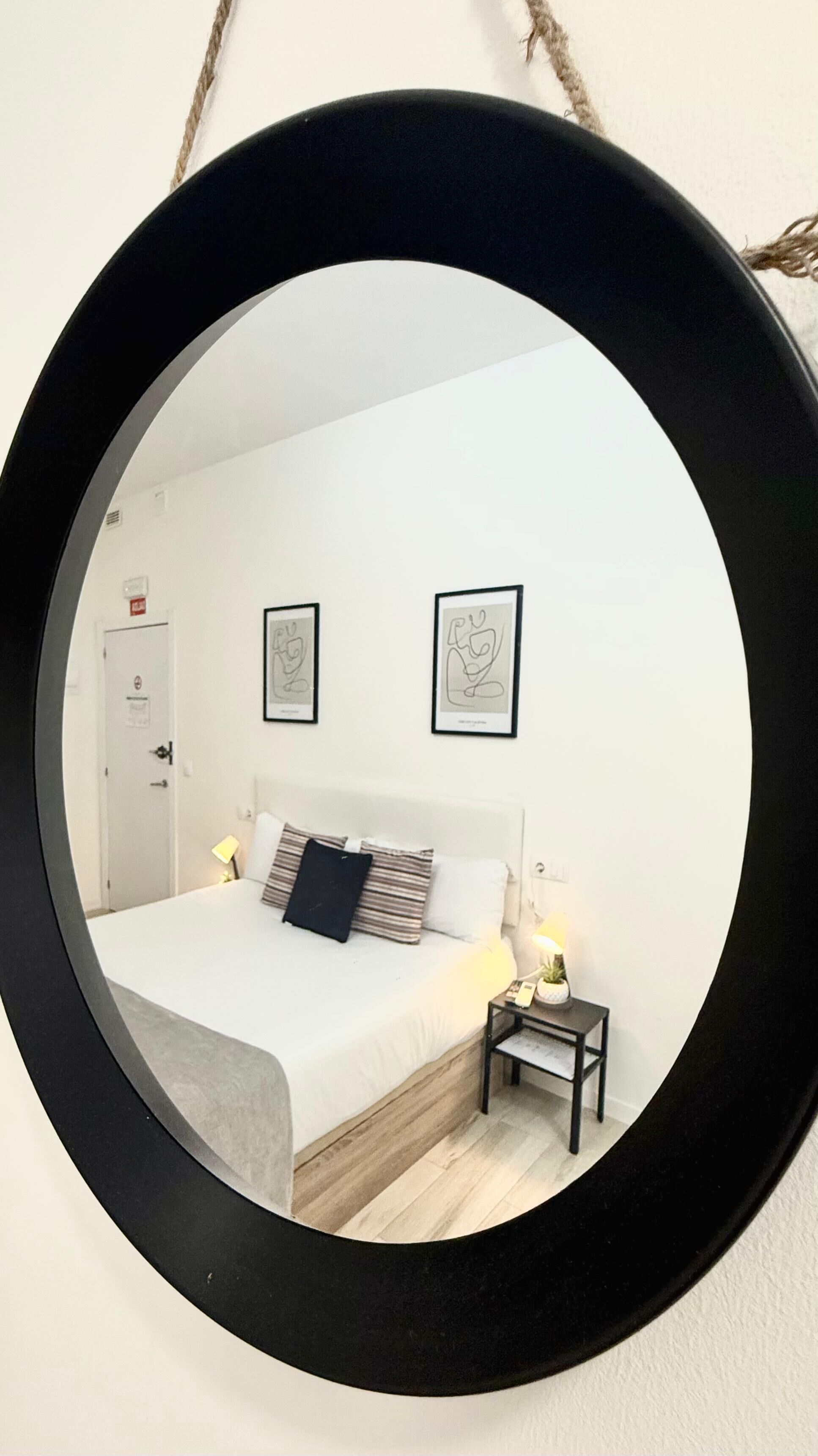 Un dormitorio con una cama, mesitas de noche, una puerta y dos cuadros enmarcados en la pared.