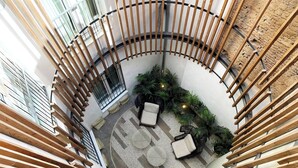 A spiral staircase with wooden railings leading to a circular outdoor seating area with cushions and plants. - Feelathome Conde Apartments (Málaga)
