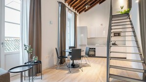 A modern apartment with a dining area, kitchen, and a staircase. - Feelathome Conde Apartments (Málaga)