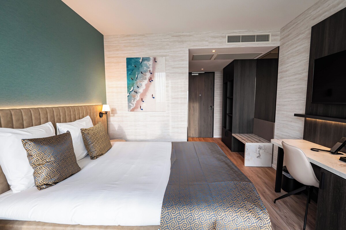 Una habitación de hotel moderna con una cama grande, un escritorio y una zona de estar.