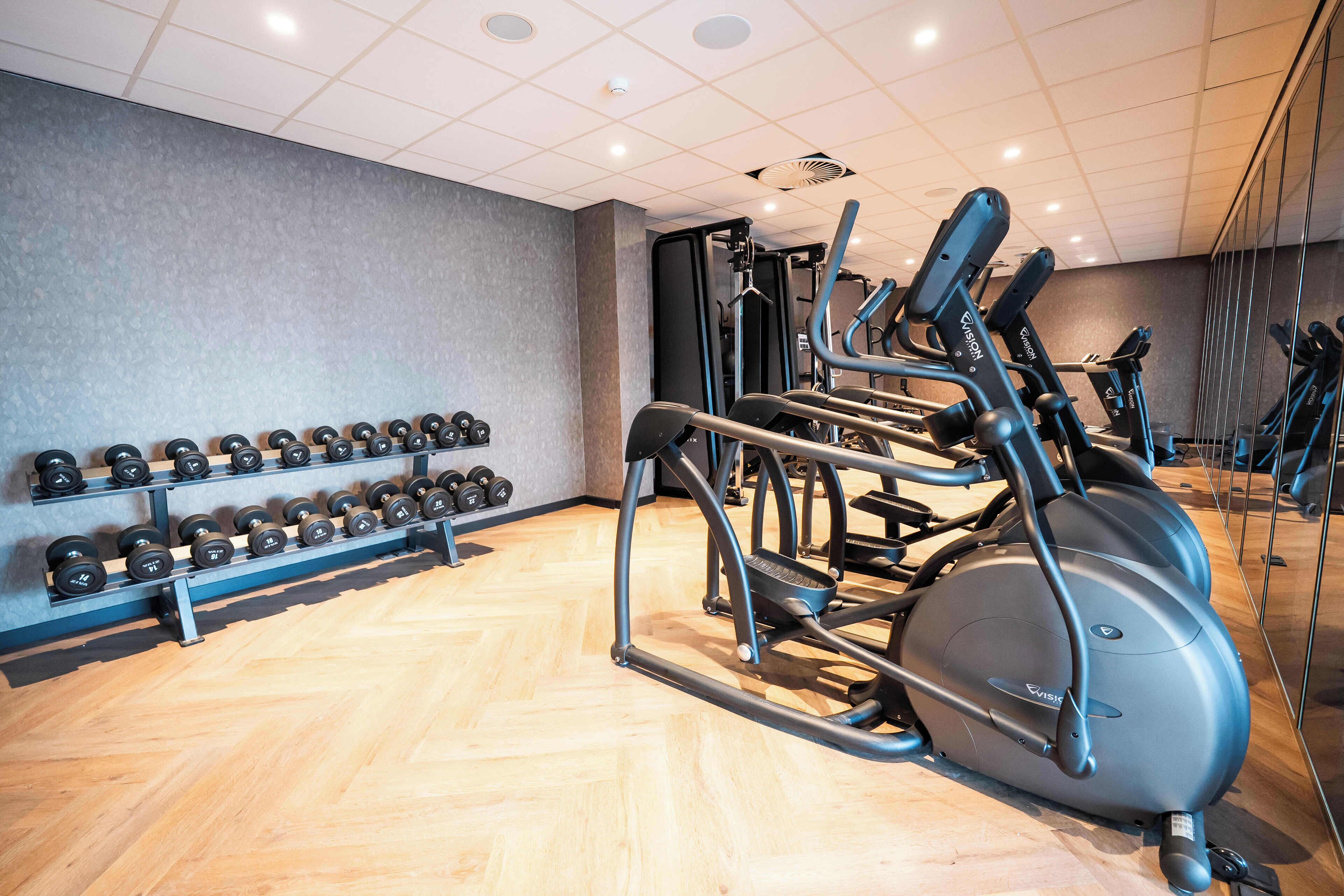 A gym with exercise equipment, including dumbbells and an elliptical machine.
