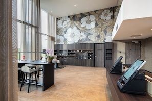 Un vestíbulo de hotel moderno con un gran mural floral, una recepción y un área de descanso.