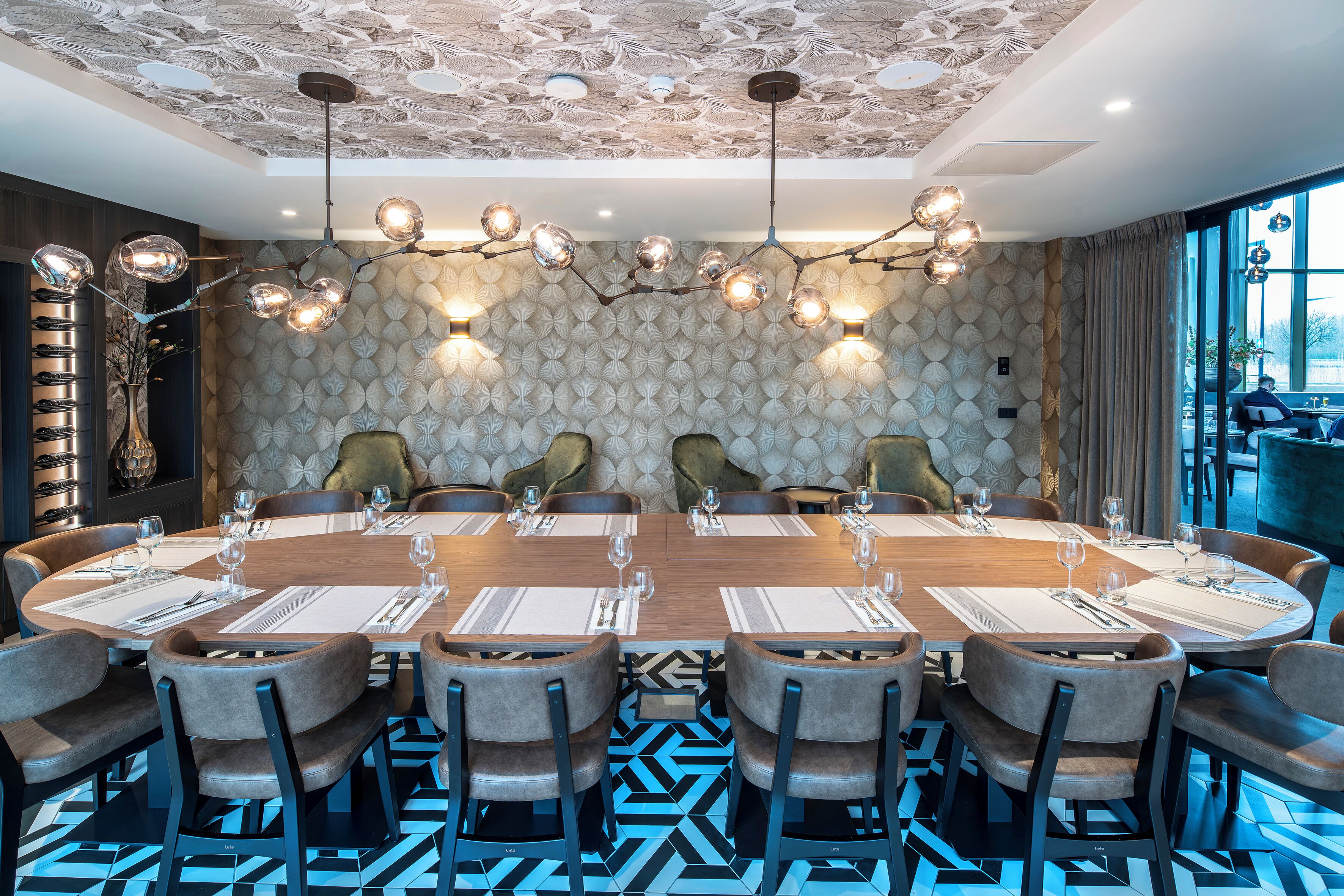 Een vergaderzaal met een ronde tafel, stoelen en een patroonplafond.