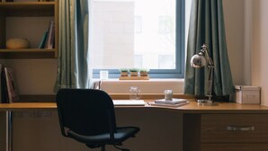 En arbetsplats med ett skrivbord, en stol, en lampa och hyllor med böcker och dekorativa föremål.