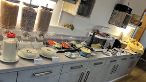 A buffet setup with various food items and containers, including yogurt, cheese, and fruits.