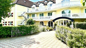 A hotel with a yellow facade, multiple balconies, and a hexagonal tile pathway.