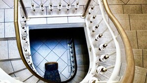 A spiral staircase with a handrail, leading to a lower level.